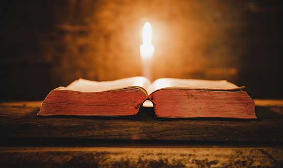 Bible with candle opened up to readers
